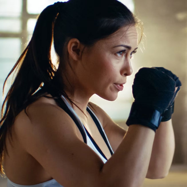 young woman with boxing gloves doing hybrid box class